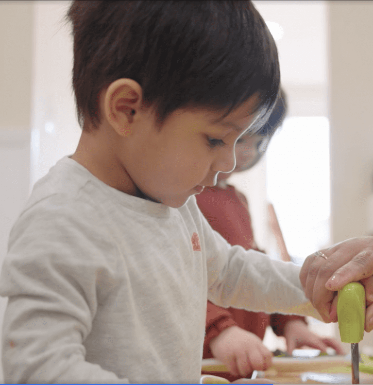 Young child using a tool to chop a vegetable